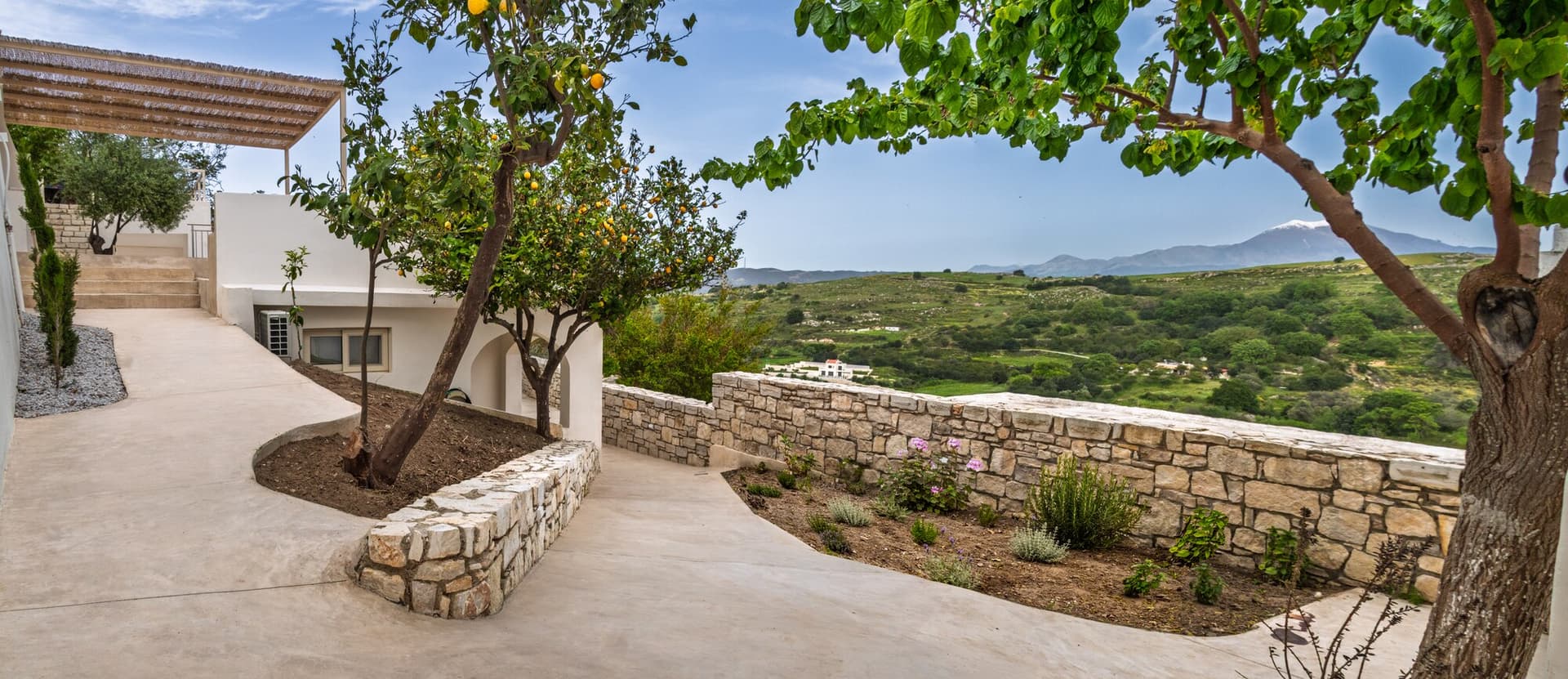 Garden path with lemon tree, white walls, and valley beyond