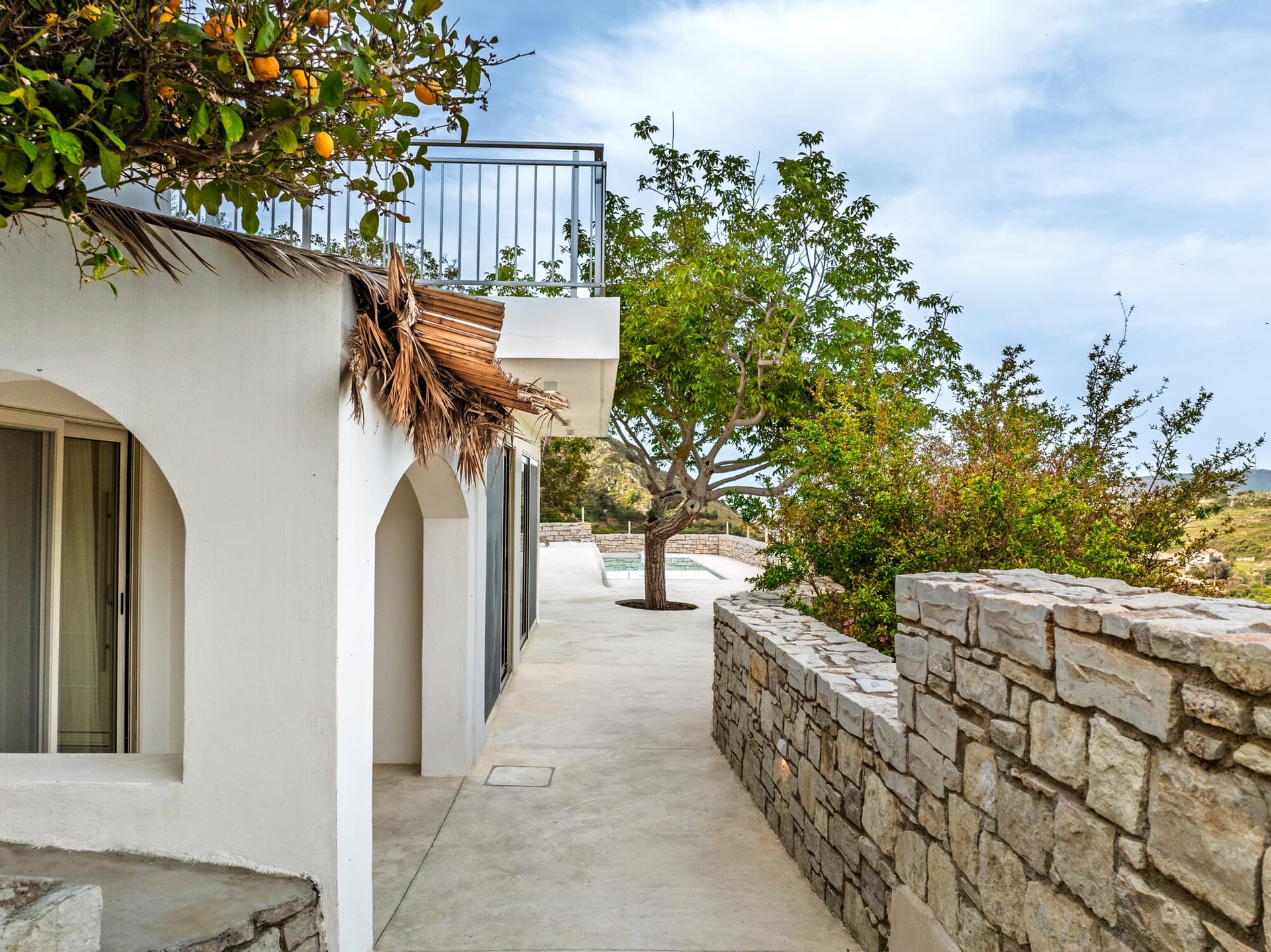 Stone path beside the white villa walls and citrus