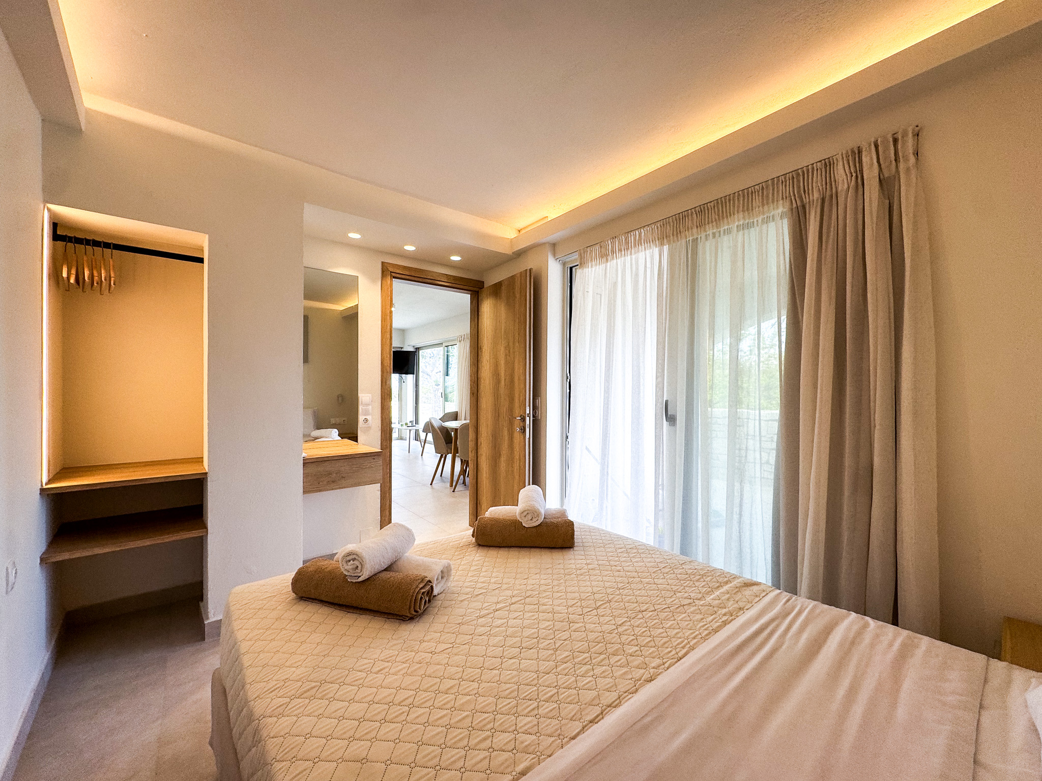 Warm bedroom with towels, balcony doors, and daylight